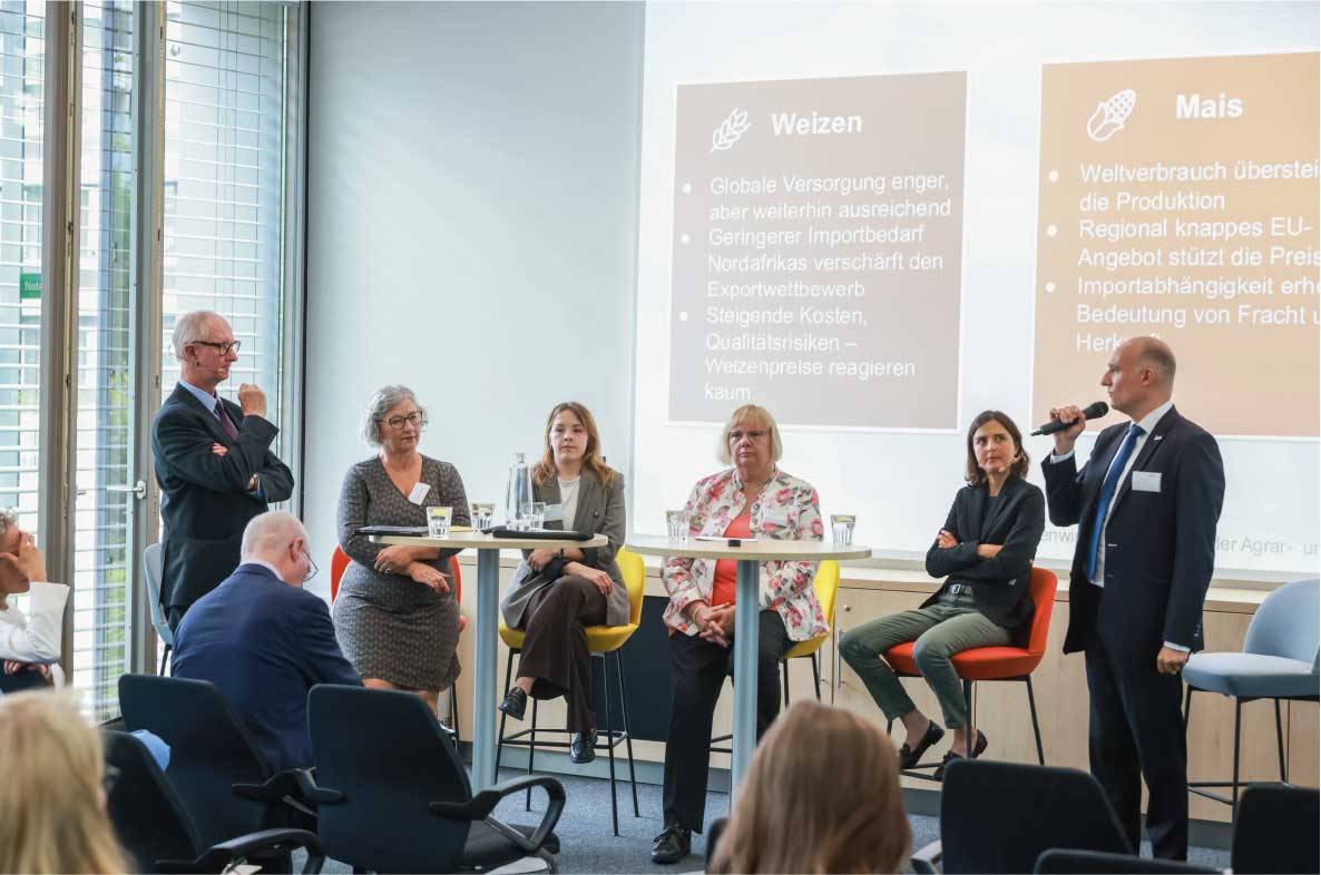 Referentin hält einen Fachvortrag auf dem 6. Außenwirtschaftsseminar der Agrar- und Ernährungswirtschaft in Bonn. Mit Mikrofon am Rednerpult erläutert sie aktuelle Entwicklungen im internationalen Agrarhandel. Im Hintergrund ist eine Präsentationsfolie mit landwirtschaftlichem Motiv zu sehen. Die Veranstaltung bringt Experten aus Wirtschaft, Politik und Verbänden zusammen, um über Exportmärkte und globale Herausforderungen für die deutsche Ernährungswirtschaft zu diskutieren.
