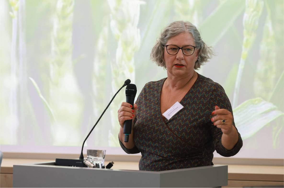 Referentin hält einen Fachvortrag auf dem 6. Außenwirtschaftsseminar der Agrar- und Ernährungswirtschaft in Bonn. Mit Mikrofon am Rednerpult erläutert sie aktuelle Entwicklungen im internationalen Agrarhandel. Im Hintergrund ist eine Präsentationsfolie mit landwirtschaftlichem Motiv zu sehen. Die Veranstaltung bringt Experten aus Wirtschaft, Politik und Verbänden zusammen, um über Exportmärkte und globale Herausforderungen für die deutsche Ernährungswirtschaft zu diskutieren.