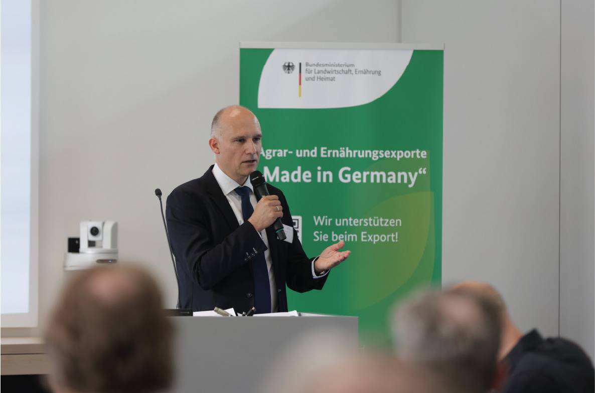 Olivier Kölsch, stellvertretender Geschäftsführer der Bundesvereinigung der Deutschen Ernährungsindustrie (BVE), spricht auf dem 6. Außenwirtschaftsseminar der Agrar- und Ernährungswirtschaft in Bonn vor Fachpublikum. Er steht am Rednerpult und erläutert aktuelle Herausforderungen und Chancen für die deutschen Agrar- und Ernährungsexporte. Im Hintergrund ist ein Banner der Exportförderinitiative „Made in Germany“ des Bundesministeriums für Landwirtschaft, Ernährung und Heimat zu sehen.