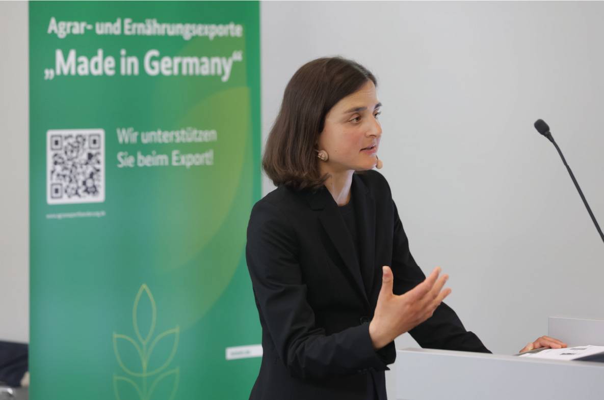 Referentin hält einen Fachvortrag auf dem 6. Außenwirtschaftsseminar der Agrar- und Ernährungswirtschaft in Bonn. Am Rednerpult erläutert sie aktuelle Entwicklungen und Herausforderungen im internationalen Agrar- und Ernährungshandel. Neben ihr steht ein Banner der Exportförderinitiative „Made in Germany“ des Bundesministeriums für Landwirtschaft, Ernährung und Heimat, das die Unterstützung deutscher Unternehmen auf internationalen Märkten hervorhebt.