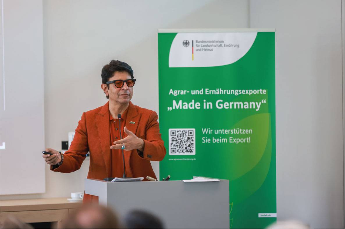 Referent spricht auf dem 6. Außenwirtschaftsseminar der Agrar- und Ernährungswirtschaft in Bonn über internationale Märkte und Exportchancen für deutsche Lebensmittel. Am Rednerpult erläutert er aktuelle Entwicklungen im Außenhandel, während im Hintergrund ein Banner der Exportförderinitiative „Agrar- und Ernährungsexporte Made in Germany“ des Bundesministeriums für Landwirtschaft, Ernährung und Heimat zu sehen ist.