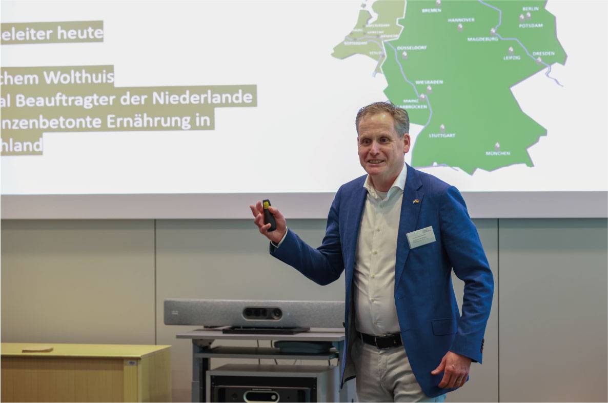Referent hält einen Vortrag auf dem 6. Außenwirtschaftsseminar der Agrar- und Ernährungswirtschaft in Bonn. Vor einer Präsentationsfolie mit Deutschlandkarte und Informationen zur pflanzenbasierten Ernährung erläutert er internationale Entwicklungen und Marktchancen für die Agrar- und Ernährungswirtschaft. Die Veranstaltung bringt Experten aus Wirtschaft, Politik und Exportförderung zusammen, um über aktuelle Trends im Außenhandel zu diskutieren.