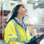 Frau in Lager für Logistik mit Tablet in der Hand.