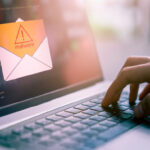 Eine Hand auf dem Keyboard eines Laptops, die gerade eine Malware-Warnung öffnet