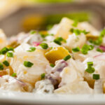 Traditioneller deutscher Kartoffelsalat mit Gurke, Zwiebel und Mayonnaise.