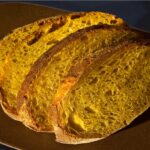 Nahaufnahme von mehreren Scheiben Solein-Brot auf einem braunen Teller. Das Brot hat eine goldgelbe Krume mit luftiger Porung und eine knusprige Kruste.
