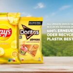 Drei Snackverpackungen von Cheetos, Lay’s und Doritos stehen nebeneinander auf einem Holztisch vor einem Naturhintergrund. Rechts daneben steht: „Alle unsere Snack-Verpackungen in Europa werden bis 2030 aus 100 % erneuerbarem oder recycelten Plastik bestehen.