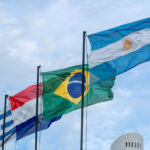 Flaggen der MERCOSUR-Staaten (Uruguay, Paraguay, Brasilien und Argentinien) wehen im Wind vor blauem Himmel