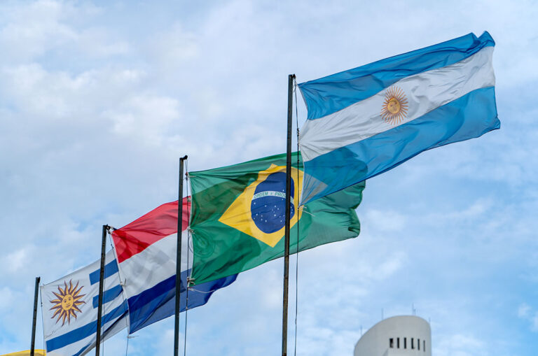 Flaggen der MERCOSUR-Staaten (Uruguay, Paraguay, Brasilien und Argentinien) wehen im Wind vor blauem Himmel