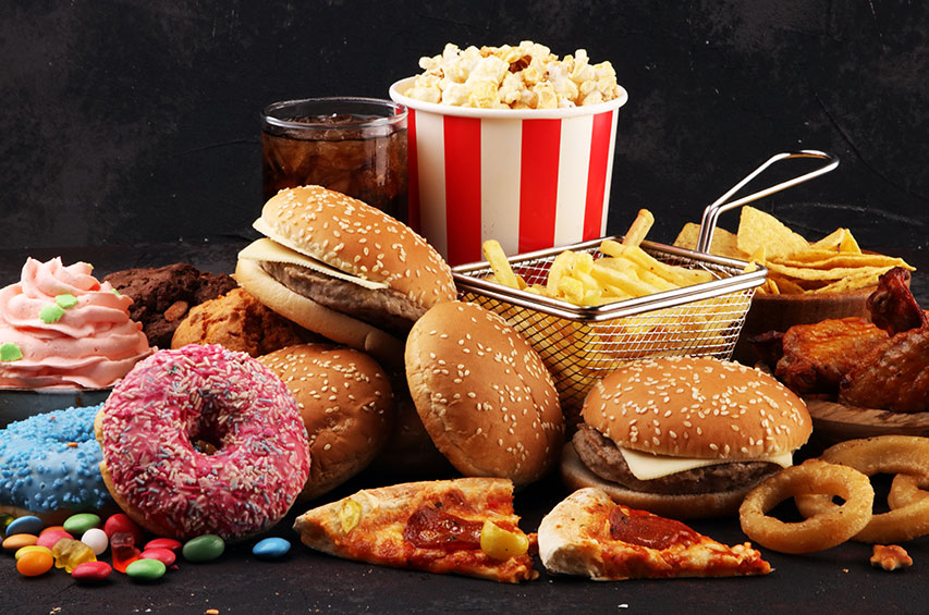 Vielfalt an Fast Food: Burger, Pommes, Pizza, Donuts, Süßigkeiten und Softdrink
