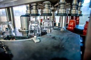 Industrielle Abfüllanlage für Tomatensoße: Leere Glasflaschen werden automatisiert befüllt – moderne Lebensmittelproduktion in der Lebensmittelindustrie