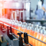 Abfüllanlage in der Lebensmittelindustrie mit Glasflaschen und Mitarbeitenden in Schutzkleidung
