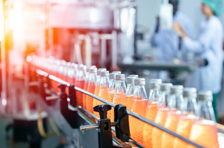 Abfüllanlage in der Lebensmittelindustrie mit Glasflaschen und Mitarbeitenden in Schutzkleidung