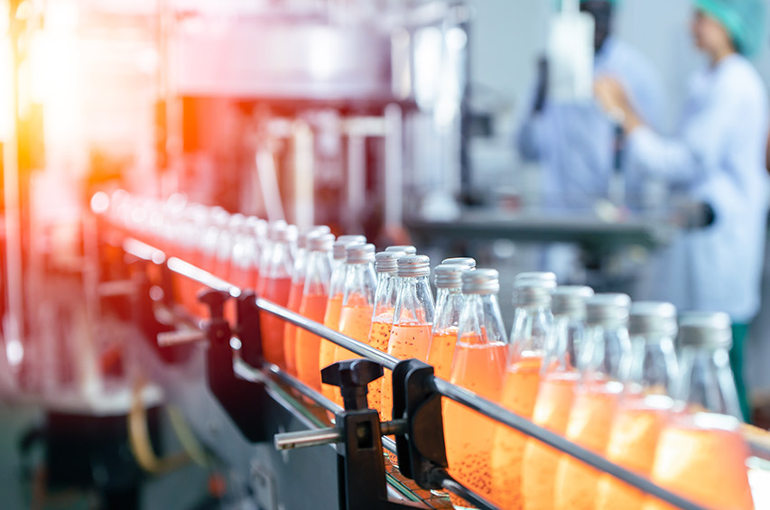 Abfüllanlage in der Lebensmittelindustrie mit Glasflaschen und Mitarbeitenden in Schutzkleidung
