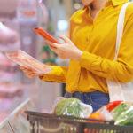 Frau scannt Lebensmittelverpackung mit Smartphone im Supermarkt