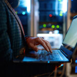 IT-Spezialist arbeitet mit Laptop im Serverraum – Symbolbild für Cybersicherheit und NIS-2 Richtlinie