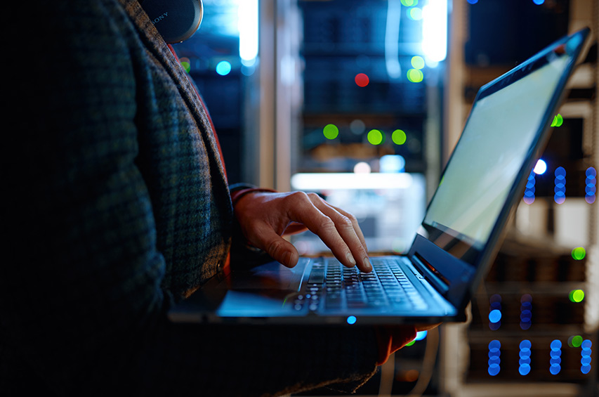 IT-Spezialist arbeitet mit Laptop im Serverraum – Symbolbild für Cybersicherheit und NIS-2 Richtlinie