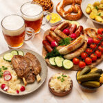 Traditionelle deutsche Speisen mit Bier, Wurst, Brezeln, Sauerkraut und Kartoffeln auf einem gedeckten Tisch
