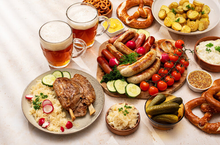 Traditionelle deutsche Speisen mit Bier, Wurst, Brezeln, Sauerkraut und Kartoffeln auf einem gedeckten Tisch