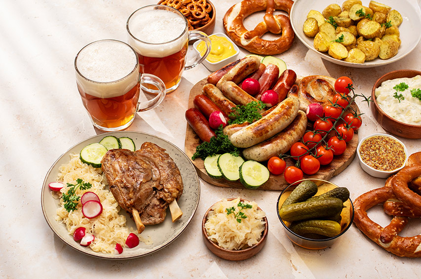 Traditionelle deutsche Speisen mit Bier, Wurst, Brezeln, Sauerkraut und Kartoffeln auf einem gedeckten Tisch