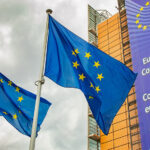 Europäische Unionsflaggen vor dem Gebäude der Europäischen Kommission unter einem bewölkten Himmel