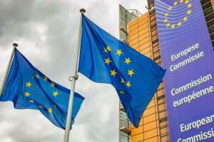 Europäische Unionsflaggen vor dem Gebäude der Europäischen Kommission unter einem bewölkten Himmel