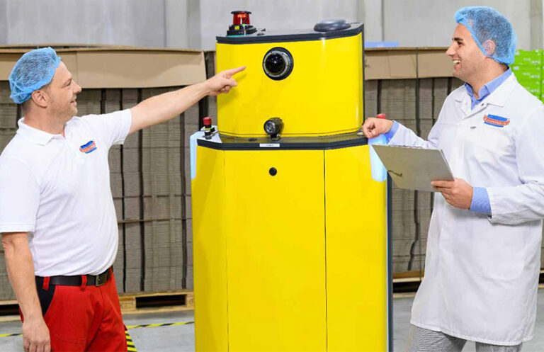 Zwei Mitarbeiter in Hygienekleidung stehen in einer Produktionshalle.