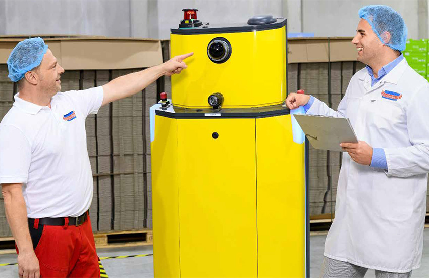 Zwei Mitarbeiter in Hygienekleidung stehen in einer Produktionshalle.