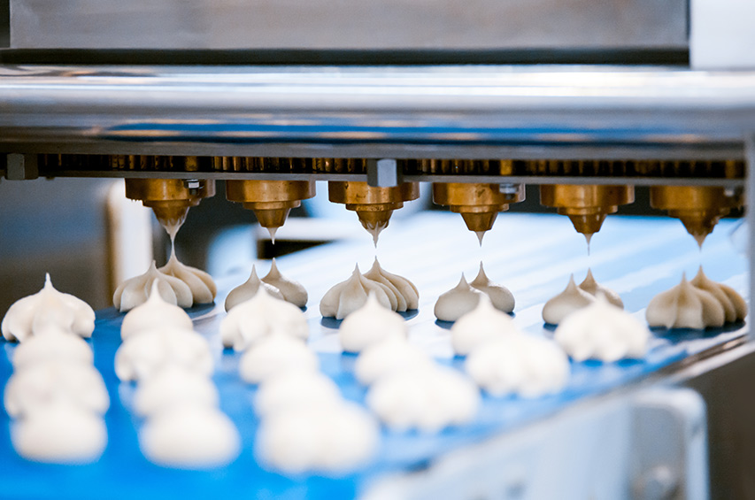 Automatisierte Dosiermaschine trägt Teigportionen auf ein Förderband in einer Lebensmittelproduktion auf.