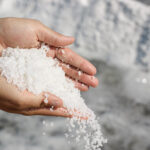 Person hält grobkörniges Salz in den Händen.