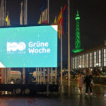Große LED-Leinwand mit dem Logo zum 100jährigen Jubiläum der Grünen Woche vor dem Messegelände Berlin bei Nacht.