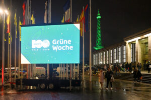 Große LED-Leinwand mit dem Logo zum 100jährigen Jubiläum der Grünen Woche vor dem Messegelände Berlin bei Nacht.