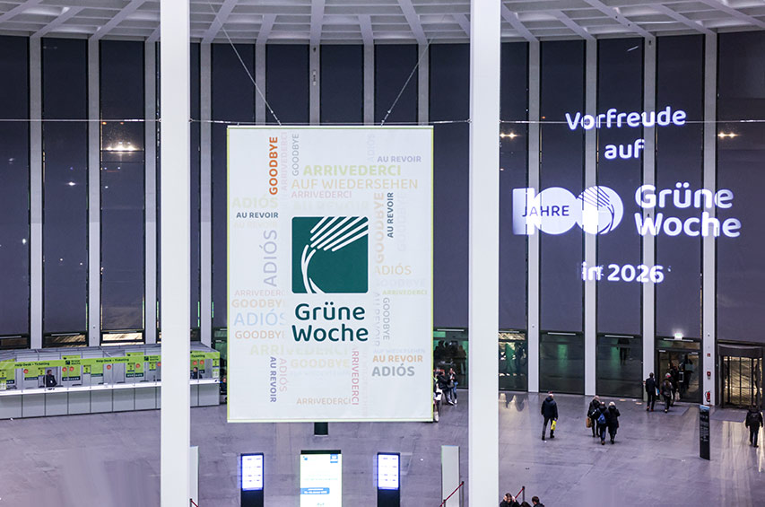 Innenraum der Messe Berlin mit großem Banner der Grünen Woche und Lichtprojektion, die auf das 100jährige Jubiläum 2026 hinweist.