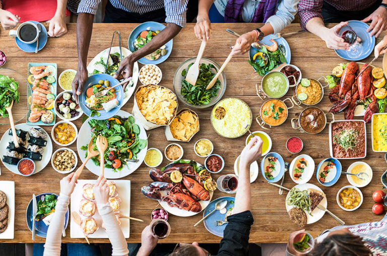 Vielfalt an Lebensmitteln auf einem gedeckten Tisch mit Gemüse, Fisch, Fleisch und Beilagen