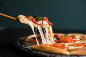 Stück Pizza mit geschmolzenem Käse als Beispiel für die Debatte um hochverarbeitete Lebensmittel und NOVA-Kritik