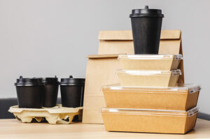 Einweg-To-go-Verpackungen und Coffee-to-go-Becher aus Kunststoff und Karton auf einem Tisch