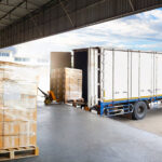 Lkw wird an einer Lagerhalle mit Paletten beladen