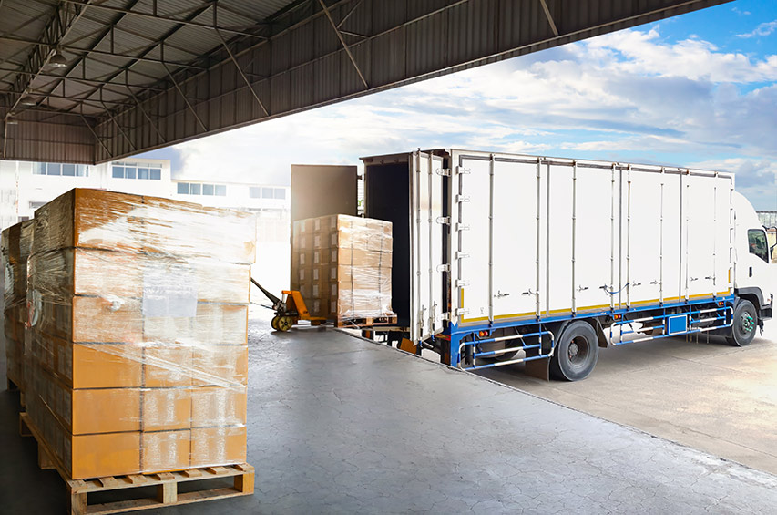 Lkw wird an einer Lagerhalle mit Paletten beladen