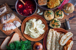 Tisch mit osteuropäischen Speisen wie Teigtaschen, Suppe und Brot.