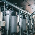 Moderne Craft-Beer-Brauerei mit großen Edelstahl-Gärtanks und Braukesseln, industrielle Bierproduktion mit professioneller Brautechnik und Rohrsystemen
