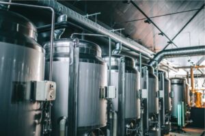 Moderne Craft-Beer-Brauerei mit großen Edelstahl-Gärtanks und Braukesseln, industrielle Bierproduktion mit professioneller Brautechnik und Rohrsystemen