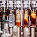 Automatisierte Abfüllanlage in der Getränkeindustrie mit Glasflaschen auf einem Förderband während des Abfüll- und Verpackungsprozesses alkoholischer Getränke in einer modernen Produktionshalle.