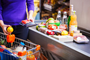 Frau legt Lebensmittel an der Supermarktkasse aufs Band.