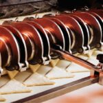 Industrielle Keksproduktion: Eine Produktionsanlage formt aus Teig gleichmäßig dreieckige Kekse auf einem Förderband.