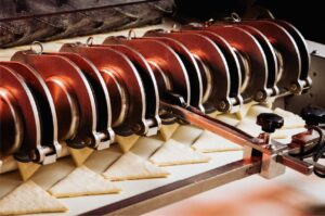 Industrielle Keksproduktion: Eine Produktionsanlage formt aus Teig gleichmäßig dreieckige Kekse auf einem Förderband.