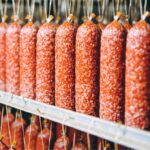 Industrielle Produktion von Wurstwaren: Reihen von Salami oder Rohwürsten in einem lebensmittelverarbeitenden Betrieb.