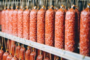 Industrielle Produktion von Wurstwaren: Reihen von Salami oder Rohwürsten in einem lebensmittelverarbeitenden Betrieb.
