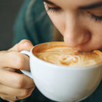 Frau trinkt eine Tasse Cappuccino mit Herz-Latte-Art