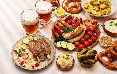 Traditionelle deutsche Speisen mit Bier, Wurst, Brezeln, Sauerkraut und Kartoffeln auf einem gedeckten Tisch