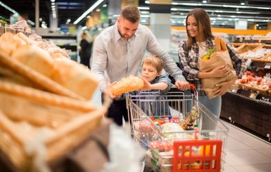Familie mit einem Kind kauft im Supermarkt ein.